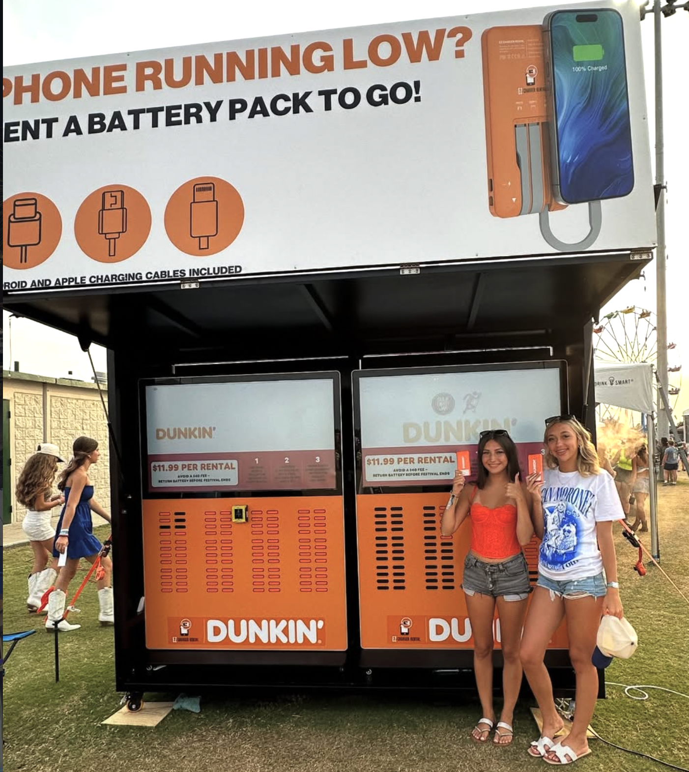 Festival guests holding branded EZ Charger power packs at a sponsor-wrapped kiosk